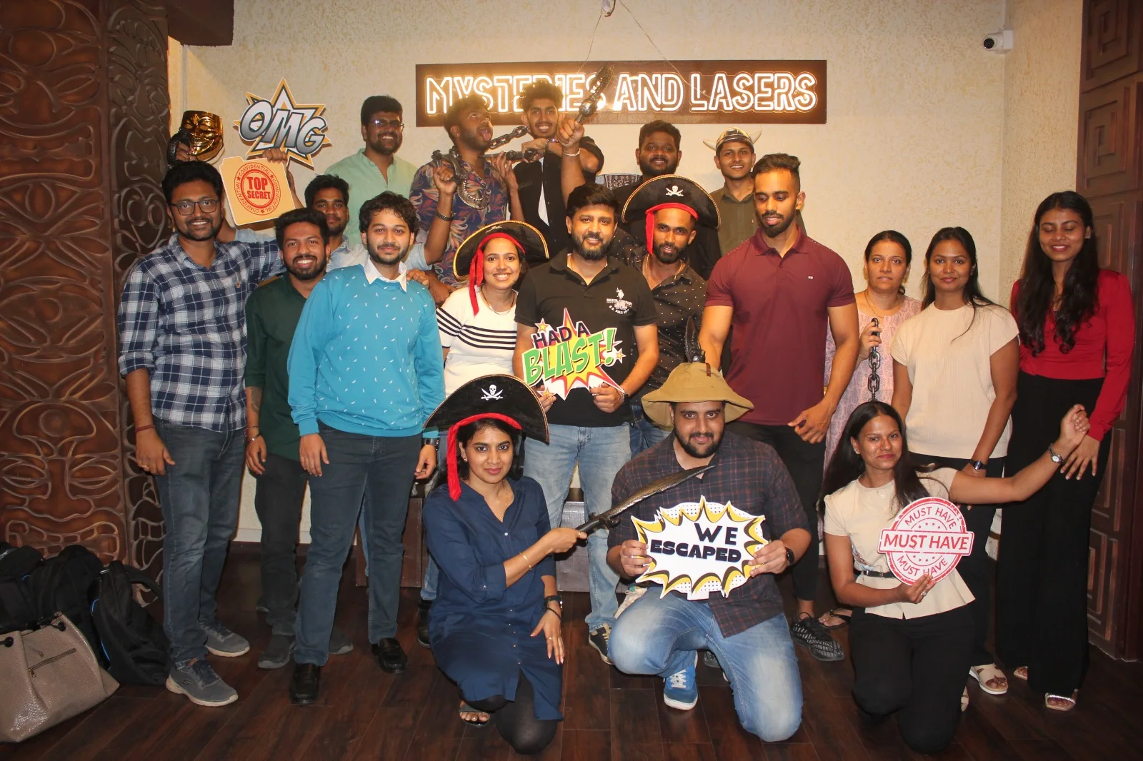 A large group celebrating with We Escaped and Had a Blast signs after their mission at Mysteries and Lasers Bengaluru